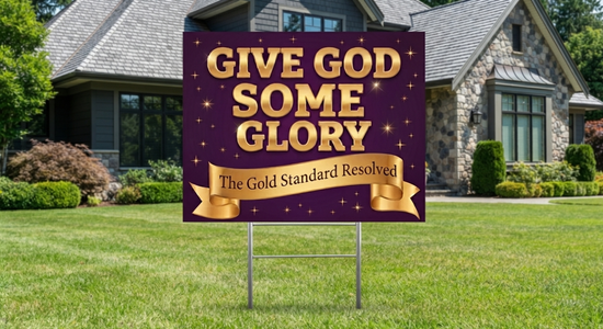A rectangular yard sign with a purple background and gold lettering that reads “GIVE GOD SOME GLORY” and “The Gold Standard Reserved,” displayed on a metal stand in a green front yard with a house in the background.