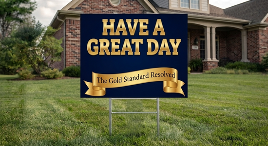 A rectangular yard sign with a dark navy blue background and large gold text reading “HAVE A GREAT DAY,” plus a gold banner reading “The Gold Standard Resolved,” displayed on a metal stand in a green lawn in front of a house.