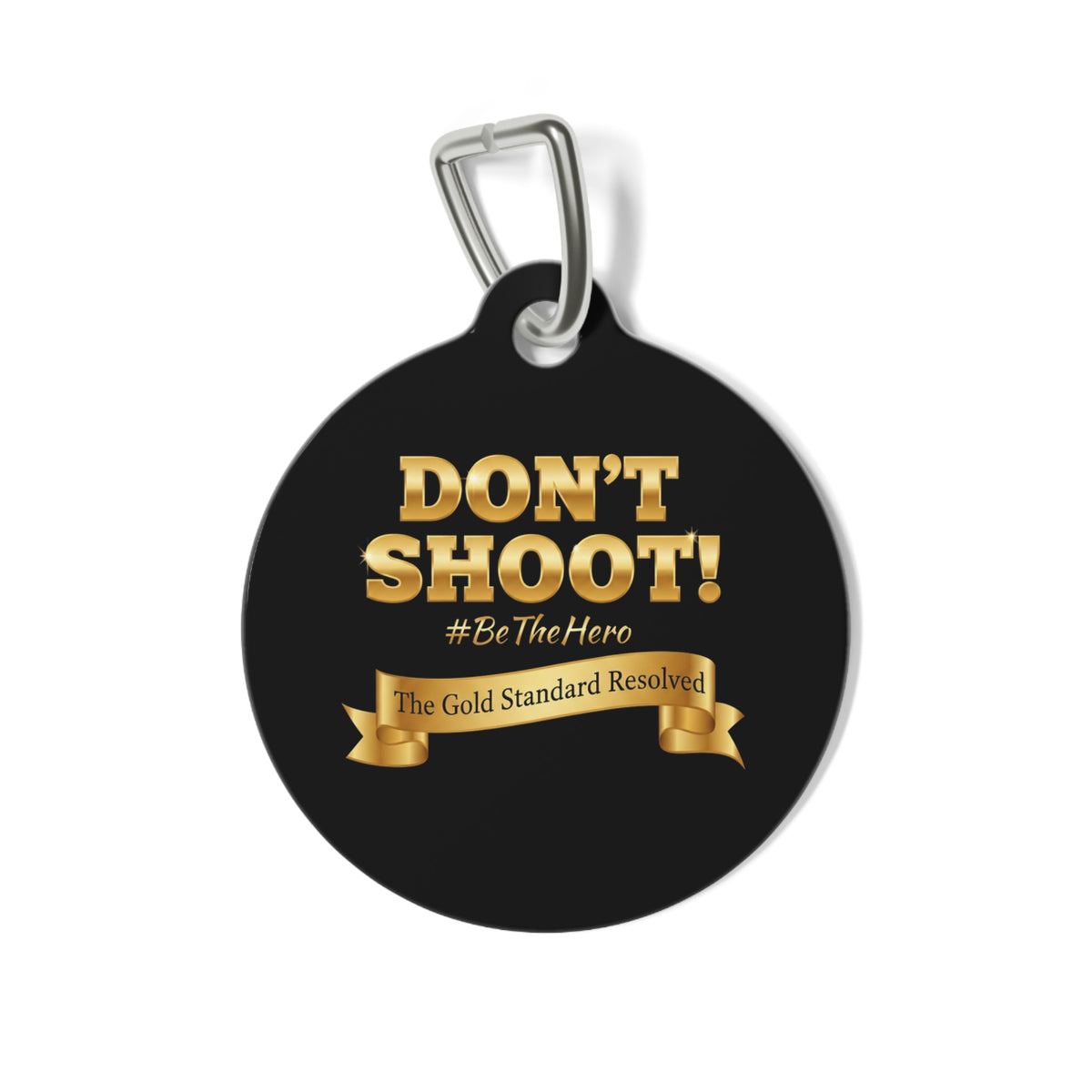 A round black pet ID tag with a silver metal clip, featuring the text 'DON'T SHOOT! #BeTheHero' and a gold ribbon banner that reads 'The Gold Standard Resolved' on a white background.